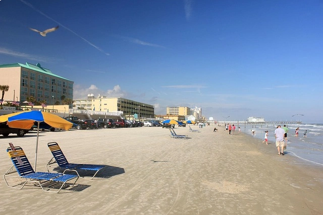 Lively scene at Daytona Beach with vintage cars and a Ferris wheel on the boardwalk