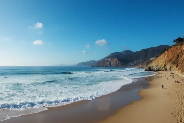 Surfers riding waves at Malibu Surfrider Beach with scenic cliffs and blue waters in the background