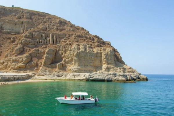 Dramatic view of Paracas Beach in Peru featuring the Paracas Candelabra, with clear emerald waters and a tour boat in the distance.